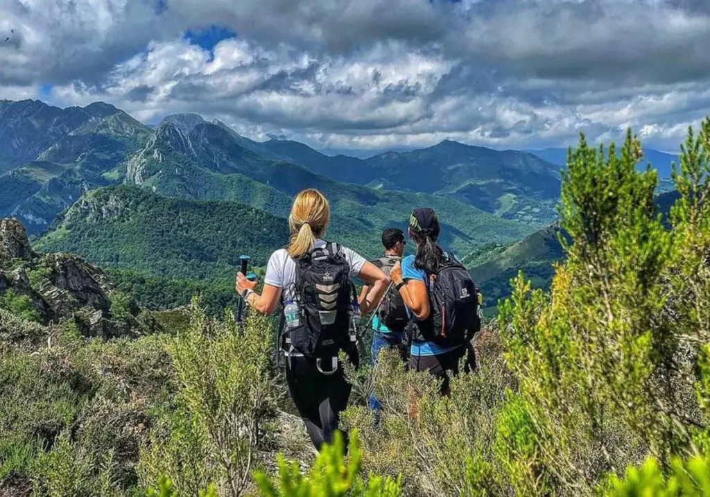 A group of hikers enjoying a hiking trail in a mountainous landscape with stunning views and partly cloudy skies.
